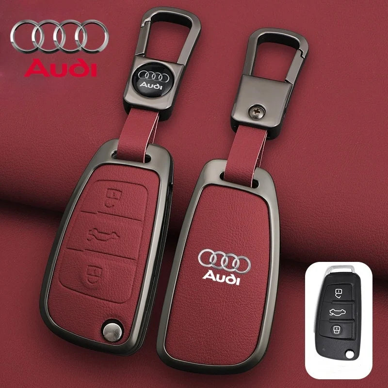 Audi key fob set with red leather cover and metallic finish on a red background.