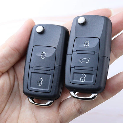 Two car key fobs held in a hand against a white background