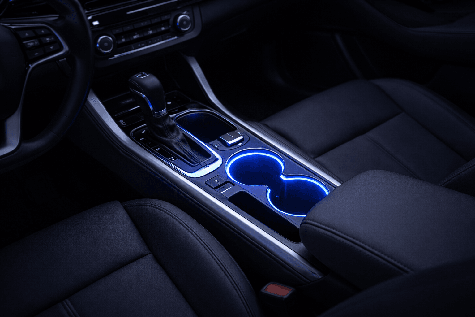Car centre console at night with blue LED illuminated cup holders