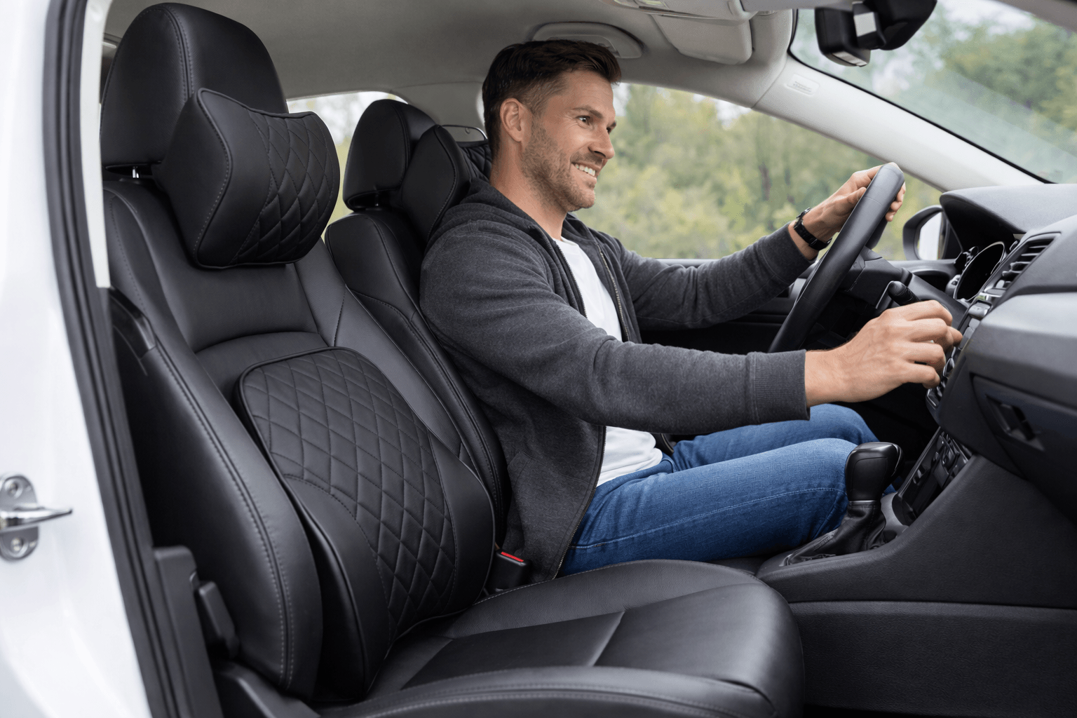 Smiling man driving a car fitted with black diamond-stitched leather seat covers