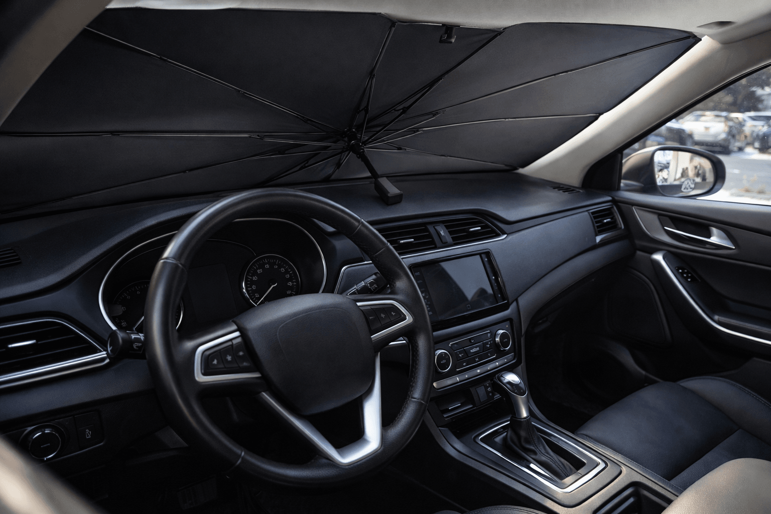 Umbrella-style windscreen sunshade open inside a car, shading the dashboard from the sun